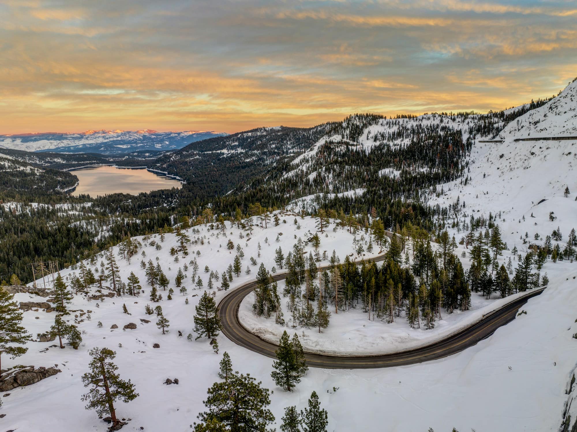 A winding mountain road through snow-dusted peaks — the road ahead